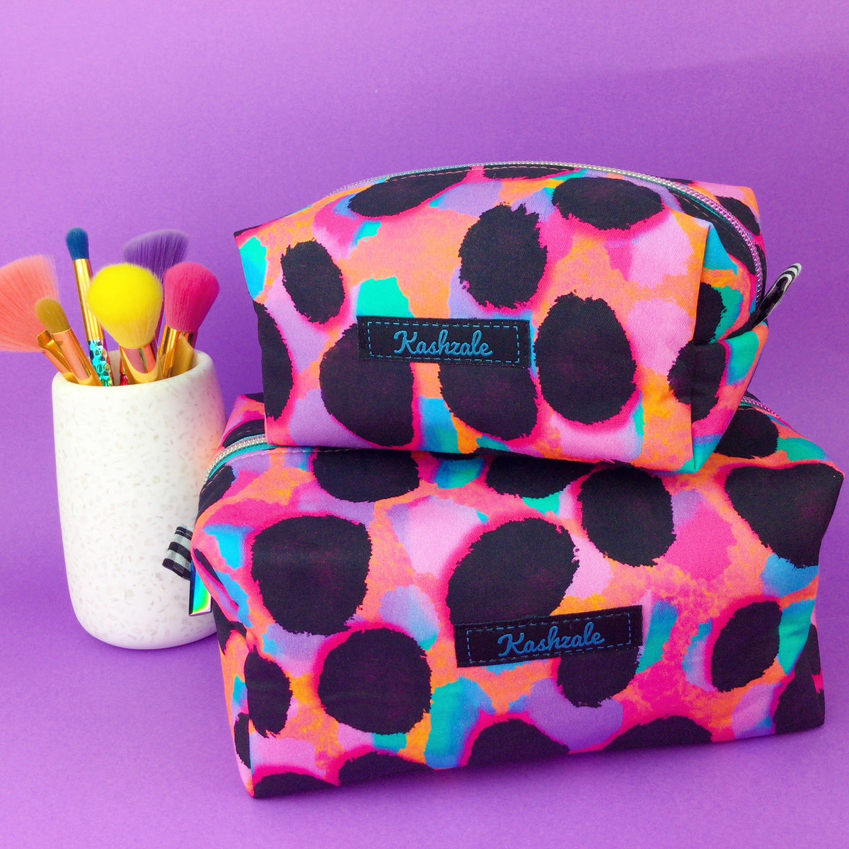 Bright Colourful small and large rectangular makeup bags on purple background. 
